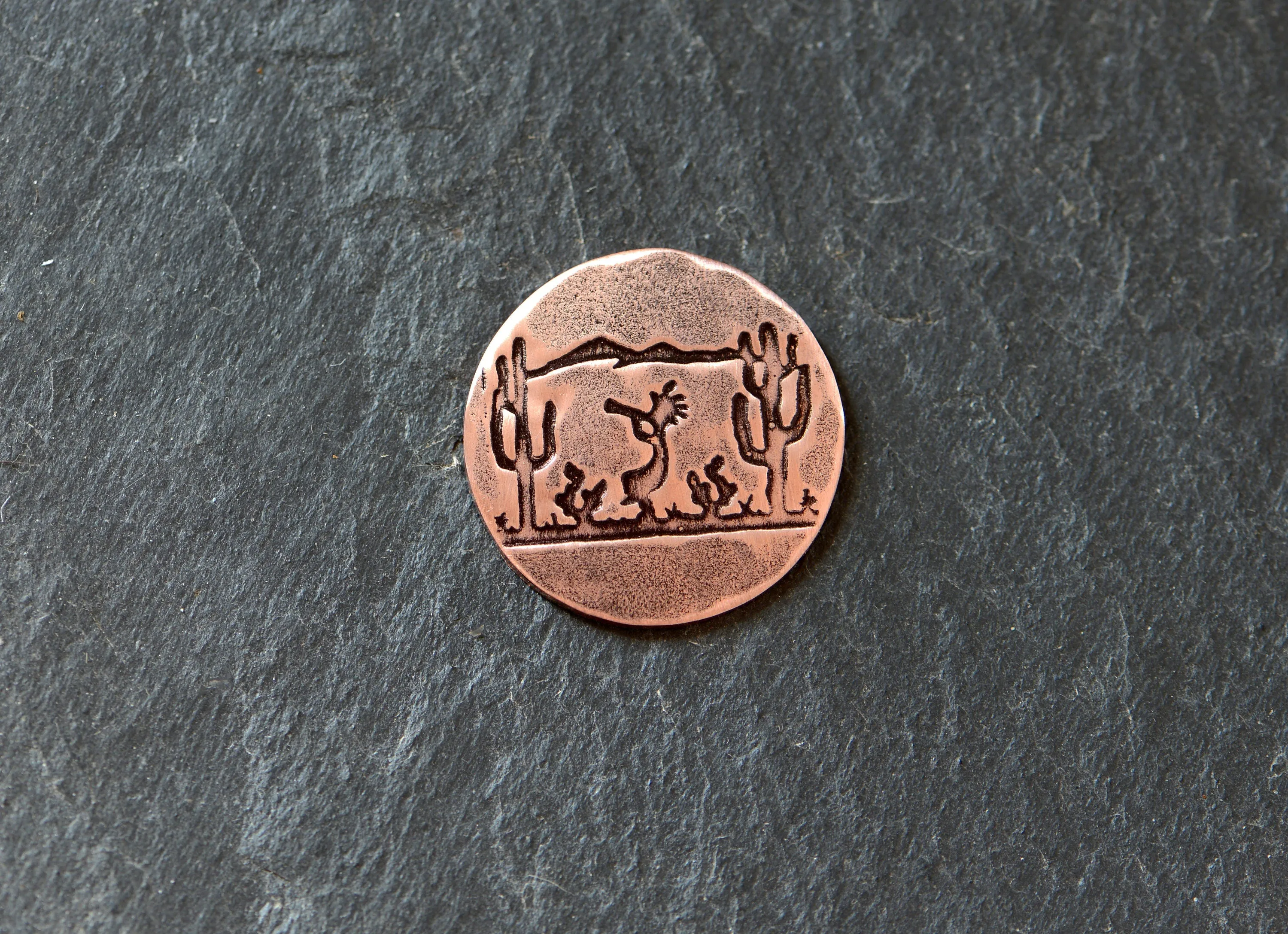 Golf ball marker with saguaro cacti and Kokopelli on copper