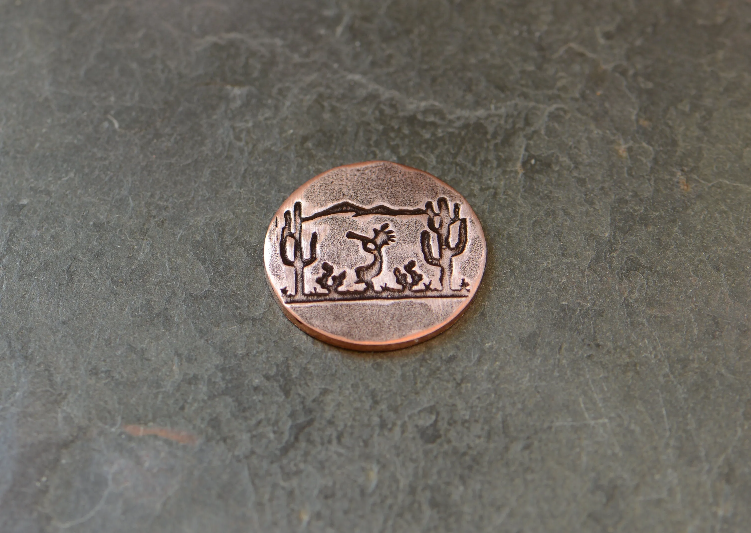 Golf ball marker with saguaro cacti and Kokopelli on copper